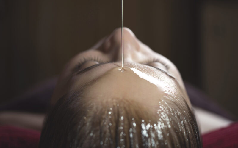 Alternative Medicine Young caucasian woman enjoying a shirodhara ayurvedic treatment.